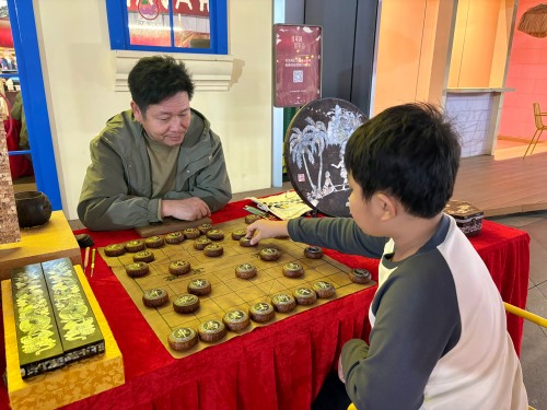 柯秋楓與市民下椰雕象棋。人民網(wǎng) 陳葉欣攝