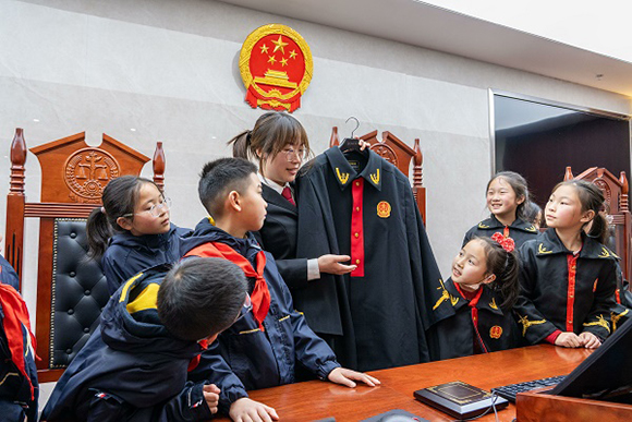 圖②：干警向同學(xué)們介紹法袍。