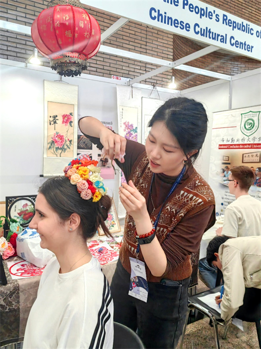 展覽正值羅馬尼亞迎春花節(jié)，國際中文教師志愿者潘婧穎向游客們介紹了國家非物質(zhì)文化遺產(chǎn)——福建泉州的簪花文化。布加勒斯特大學(xué)孔子學(xué)院供圖。