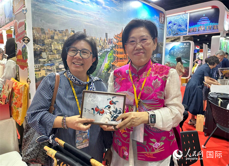 中國“大冶刺繡”傳承人劉小紅（右）參加泰國國際旅游展，向觀眾介紹中國非遺刺繡針法。人民網(wǎng)記者 簡承淵攝