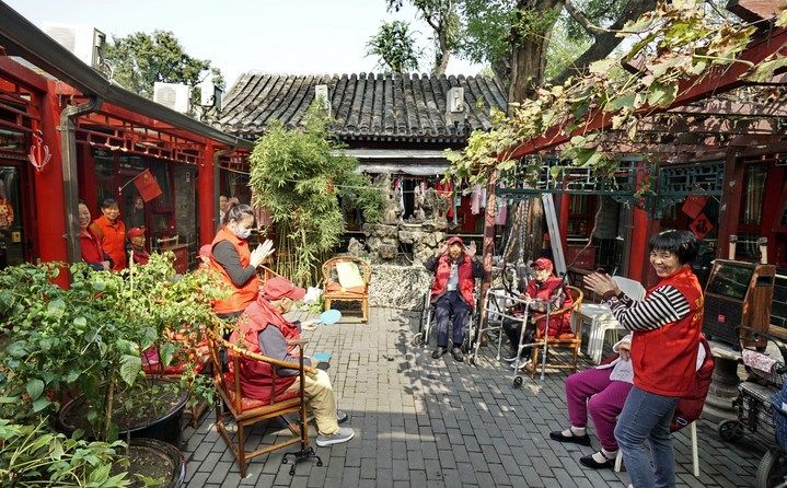 2024年10月12日，鐘樓灣胡同的老年人在社區(qū)內(nèi)的四合院養(yǎng)老驛站休閑。2017年起，北京市先后開(kāi)展了兩輪背街小巷環(huán)境整治提升行動(dòng)，完整保留了中軸線生活建筑群的歷史信息，并根據(jù)居民的生活和居住方式進(jìn)行適配化的更新和改造，極大地改善了生活環(huán)境。2023年鐘樓灣胡同被評(píng)為“北京最美街巷”。